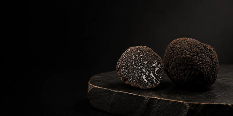 Truffe noire fraîche – Tuber melanosporum – à l'intérieur marbré présenté sur une pierre foncée