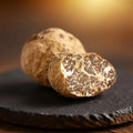 Truffes fraîches de catégorie EXTRA Tuber borchii, avec un spécimen coupé montrant l'intérieur brun naturellement veiné