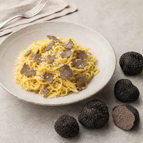 Fines lamelles de truffes noires chinoises fraîches Tuber indicum sur un plat salé raffiné