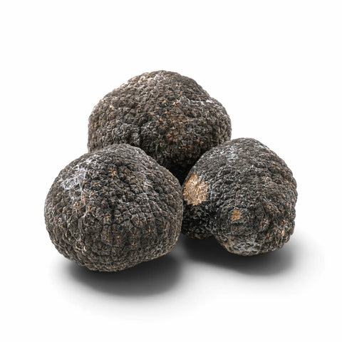 Trois truffes entières surgelées, légèrement givrées sur fond blanc